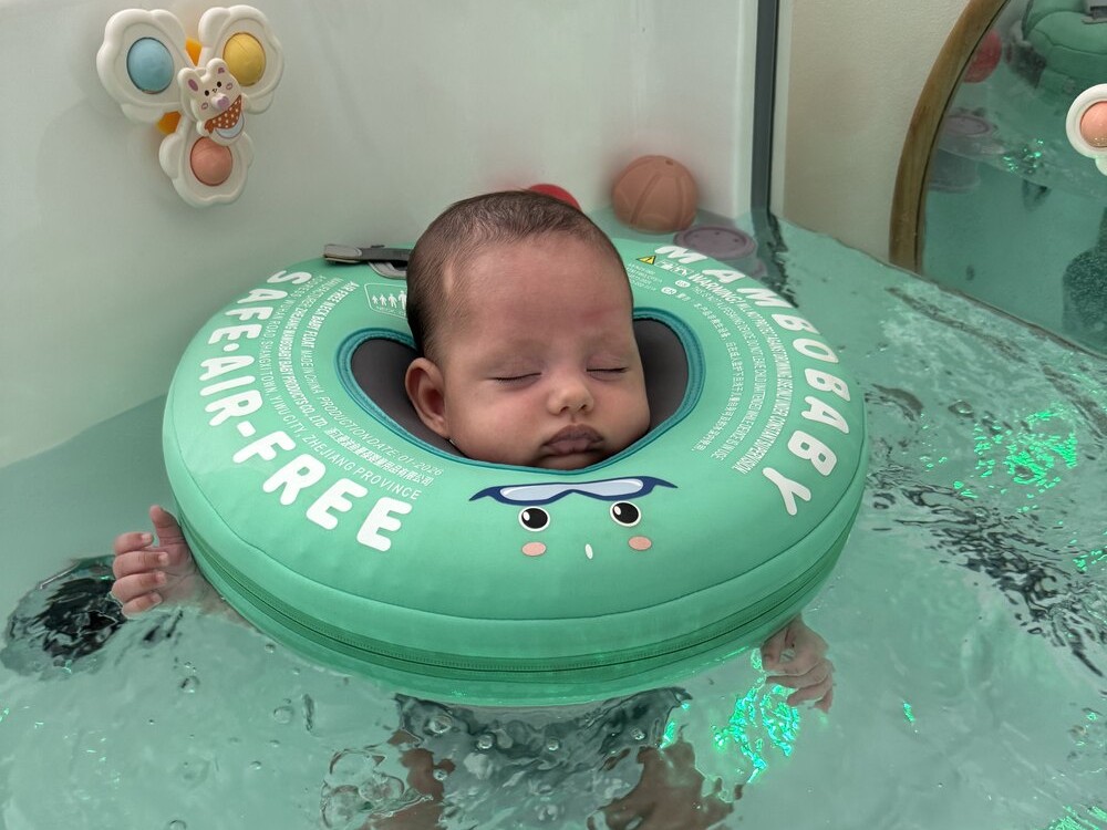 Bebé a flutuar com boia verde, visto de cima, numa sessão de baby spa em sala individual