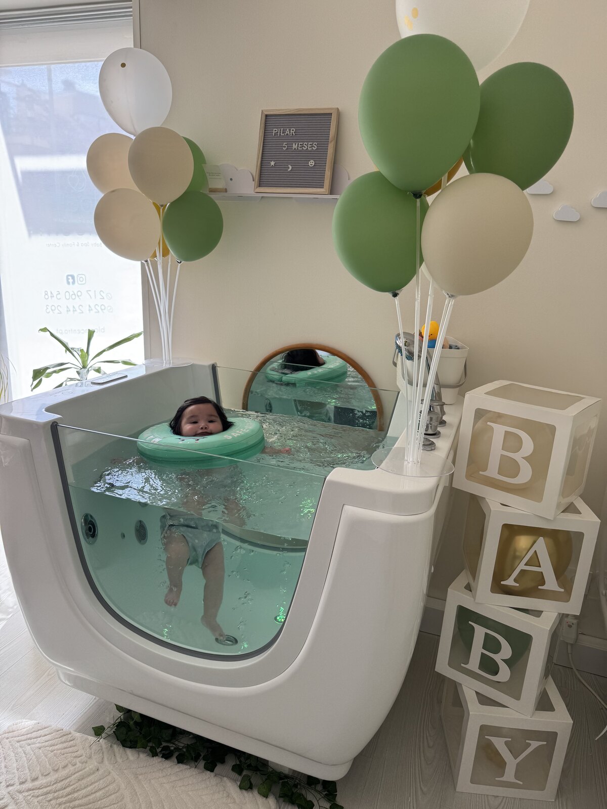 Bebé a flutuar na banheira decorada com balões para celebrar os meses