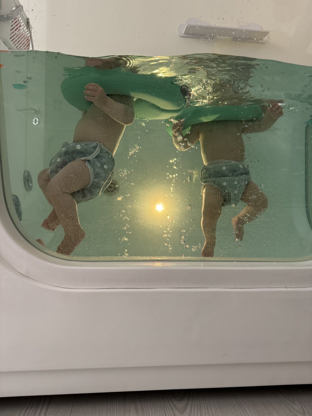 Dois bebés a observar através do vidro da sala de água